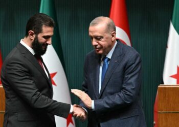 Turkish President Recep Tayyip Erdogan (R) and Syria's interim president Ahmed al-Sharaa shake hands during a joint press conference following their meeting at the Presidential Palace in Ankara, on February 4, 2025. Syria's interim president is in Turkey for talks with the country's leader after flying in from Saudi Arabia, where he was seeking help from wealthy Gulf countries to finance the reconstruction of his war-ravaged nation and revive its economy, as part of his second international trip since ousting the former Syrian president. (Photo by OZAN KOSE / AFP)