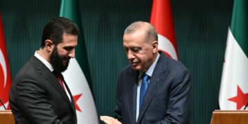 Turkish President Recep Tayyip Erdogan (R) and Syria's interim president Ahmed al-Sharaa shake hands during a joint press conference following their meeting at the Presidential Palace in Ankara, on February 4, 2025. Syria's interim president is in Turkey for talks with the country's leader after flying in from Saudi Arabia, where he was seeking help from wealthy Gulf countries to finance the reconstruction of his war-ravaged nation and revive its economy, as part of his second international trip since ousting the former Syrian president. (Photo by OZAN KOSE / AFP)