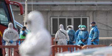 Passengers wearing a blue protective suits board a military bus after being evacuated from the Dutch flagged hantavirus-stricken cruise ship MV Hondius at the industrial port of Granadilla de Abona on the island of Tenerife in Spain's Canary Islands on May 10, 2026. Repatriation flights for the nearly 150 passengers onboard the ship hit by a deadly hantavirus outbreak began as passengers were transferred to shore on smaller vessels then by bus to the airport to be flown home after weeks at sea. (Photo by JORGE GUERRERO / AFP)