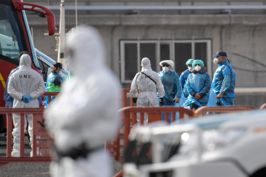 Passengers wearing a blue protective suits board a military bus after being evacuated from the Dutch flagged hantavirus-stricken cruise ship MV Hondius at the industrial port of Granadilla de Abona on the island of Tenerife in Spain's Canary Islands on May 10, 2026. Repatriation flights for the nearly 150 passengers onboard the ship hit by a deadly hantavirus outbreak began as passengers were transferred to shore on smaller vessels then by bus to the airport to be flown home after weeks at sea. (Photo by JORGE GUERRERO / AFP)