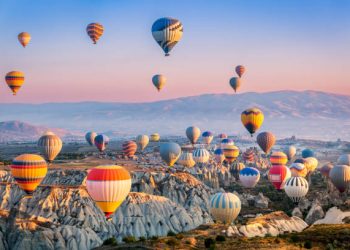 Aerial view of a fleet of hot air balloons, in Cappadocia, Turkey, at sunrise. Cappadocia is a popular tourist destination.